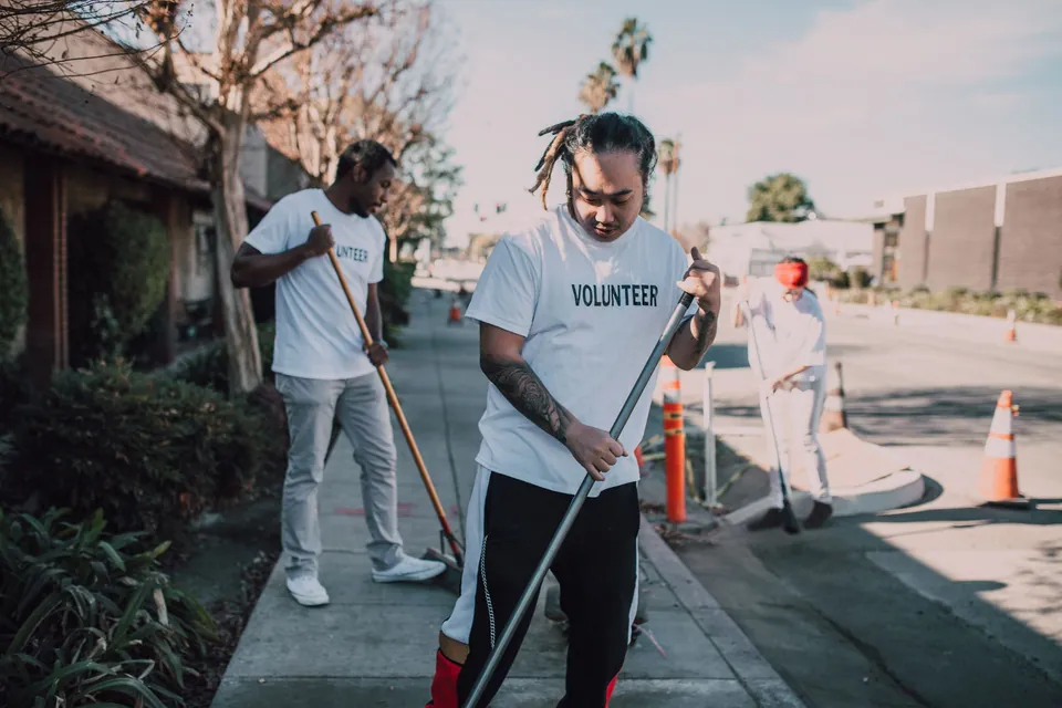 Volunteers sweeping a pavement during a neighbourhood clean-up.