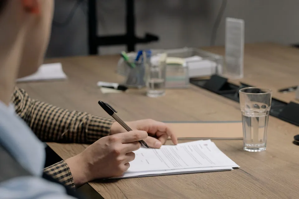 Hand signing a document during a meeting at a table.