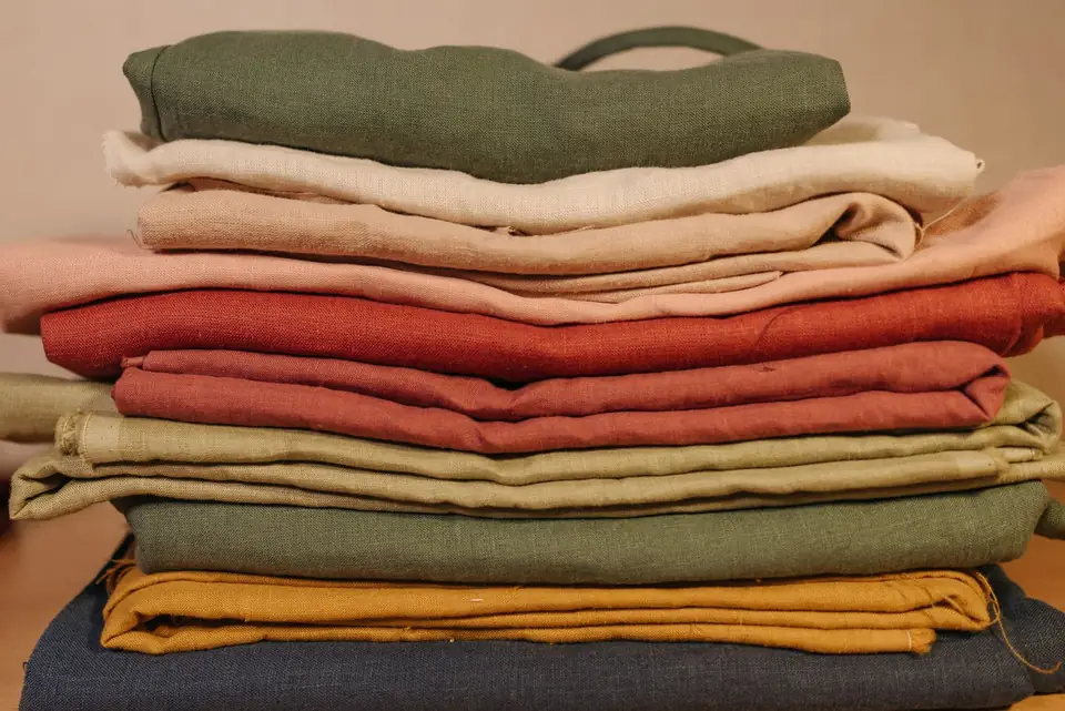 Stack of neatly folded coloured linen fabrics.