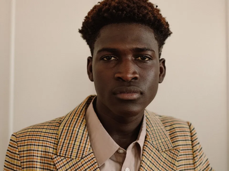 Young man in a checked jacket and light shirt, front portrait.