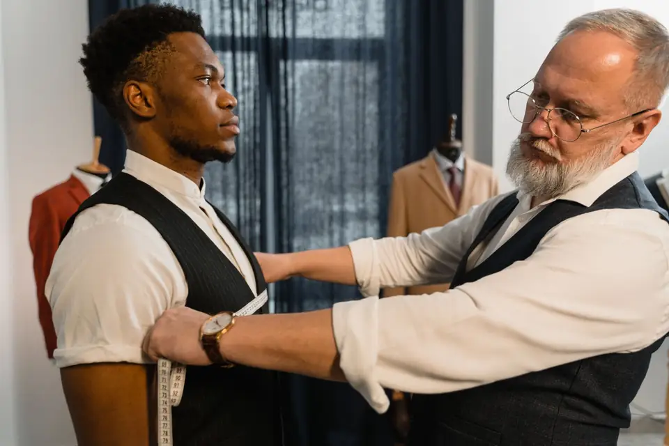 Tailor taking a client’s measurements during a fitting.