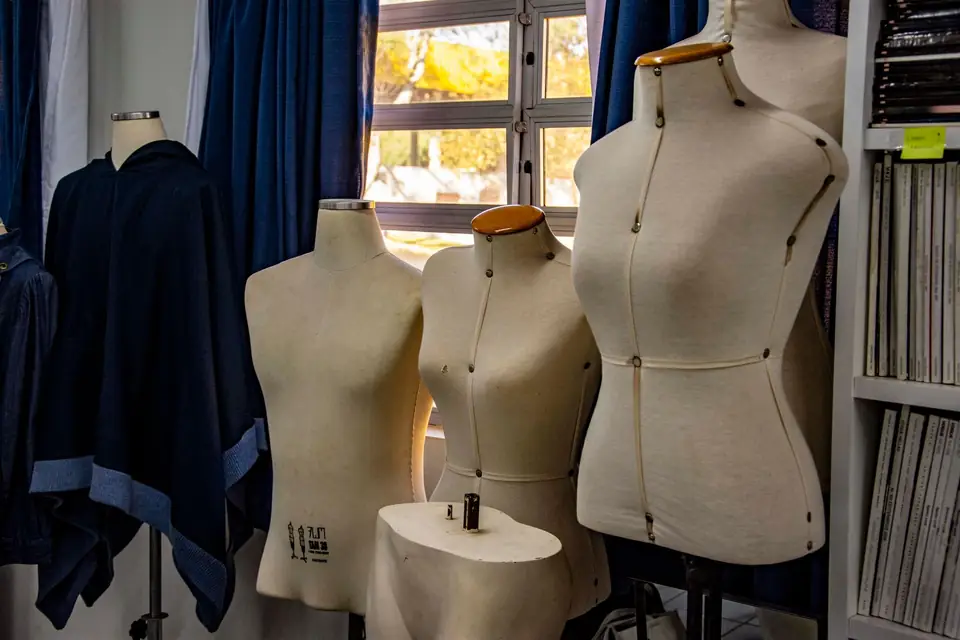 Dress forms lined up by the window of a design studio.