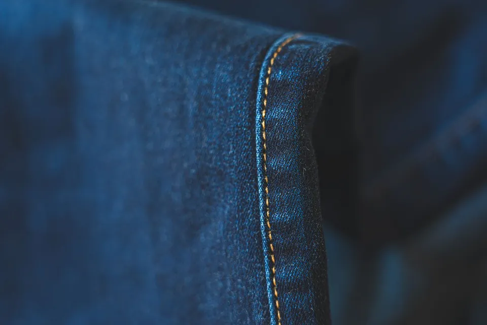Close-up of the topstitched hem of a pair of jeans.