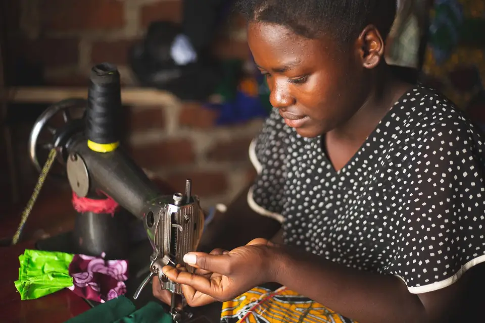 Young seamstress focused on her sewing machine in a workshop.