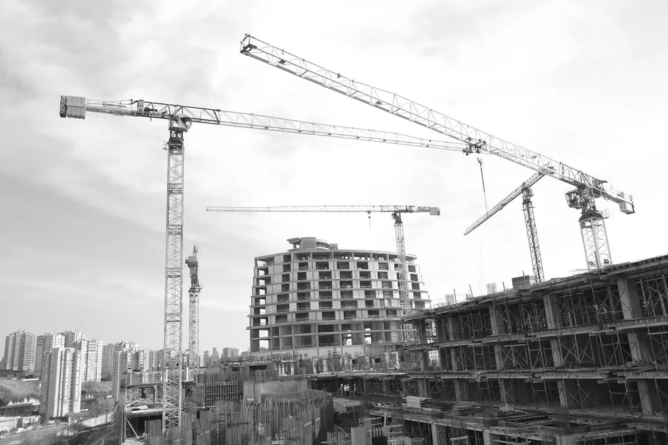 Tower cranes above a building under construction, black and white.