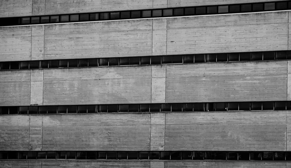 Raw concrete facade striped with long ribbon windows, black and white.
