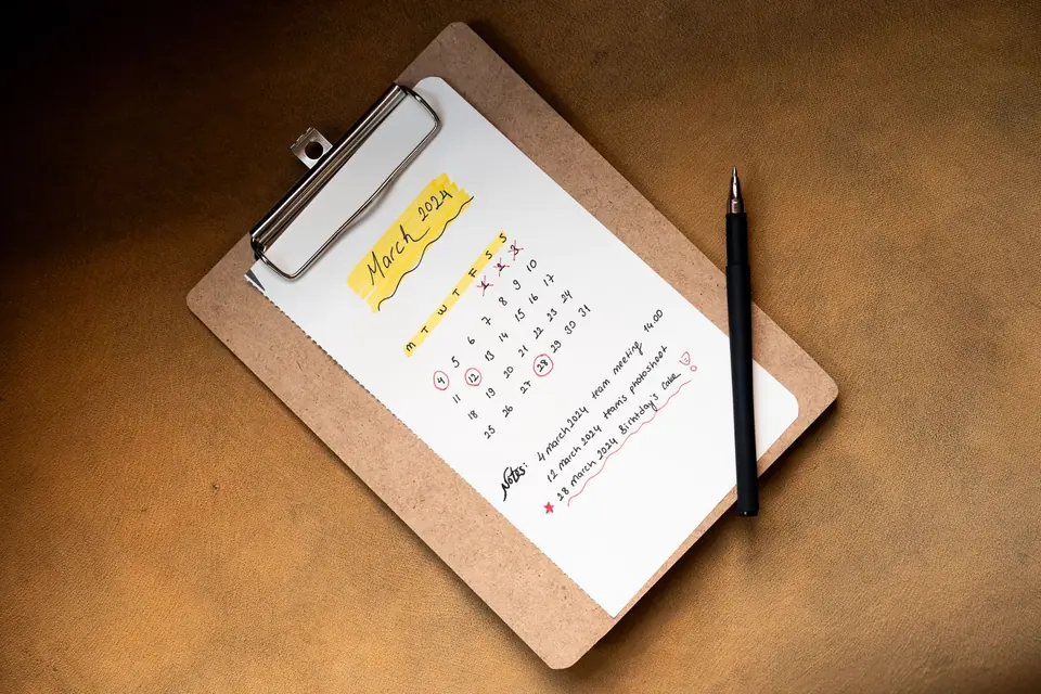 Monthly calendar on a clipboard with a pen to note an appointment.