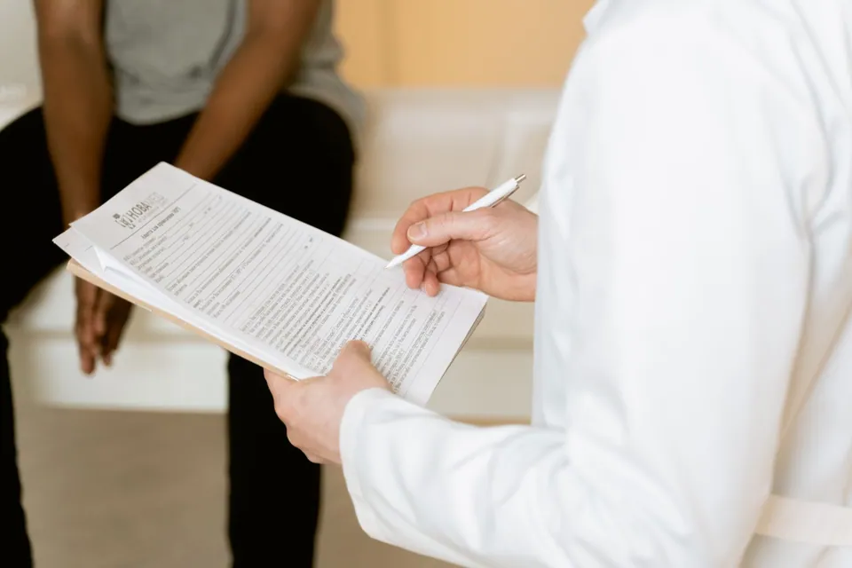Professionnel de santé consultant un formulaire médical pendant un rendez-vous.