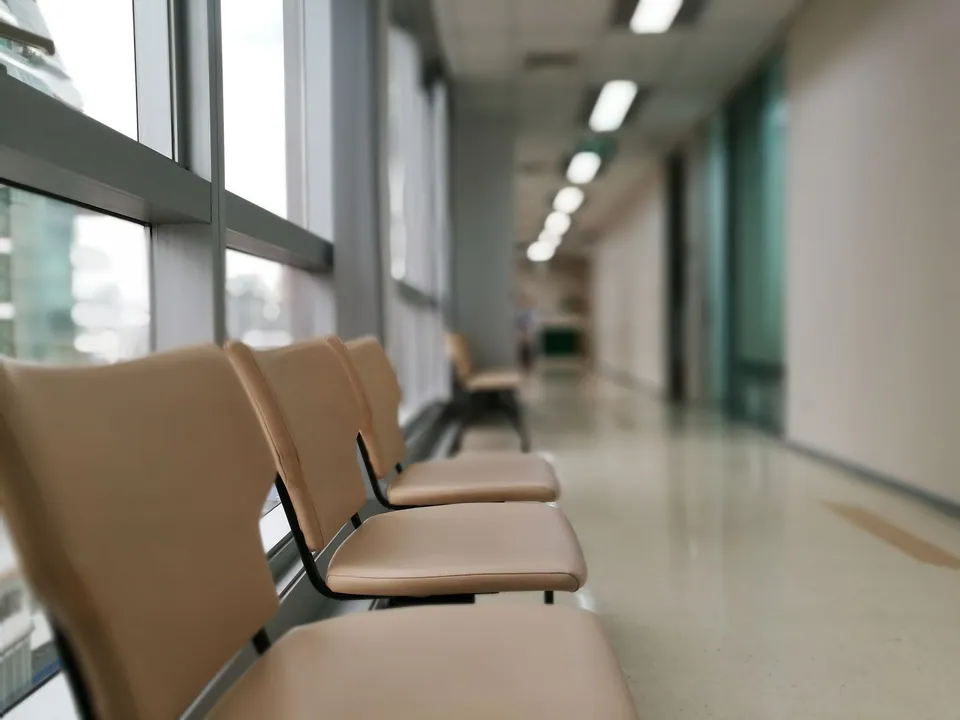 Rangée de sièges vides dans un couloir médical moderne et calme.
