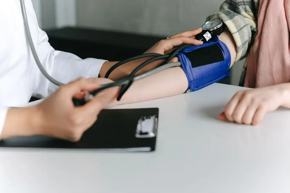 Caregiver measuring a patient’s blood pressure, only hands visible.