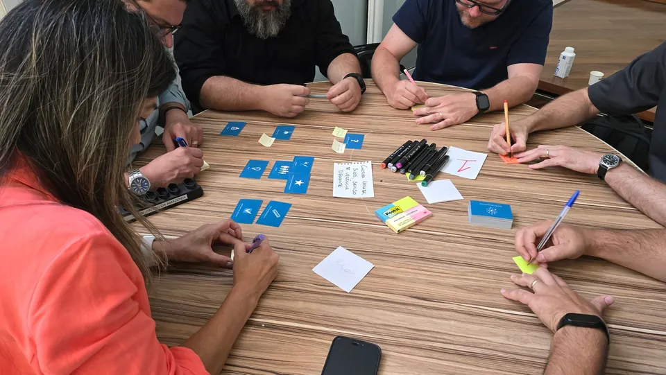 Participants around a table covered with cards, notes and markers during a workshop.