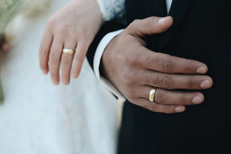 The couple’s hands and their gold wedding rings.