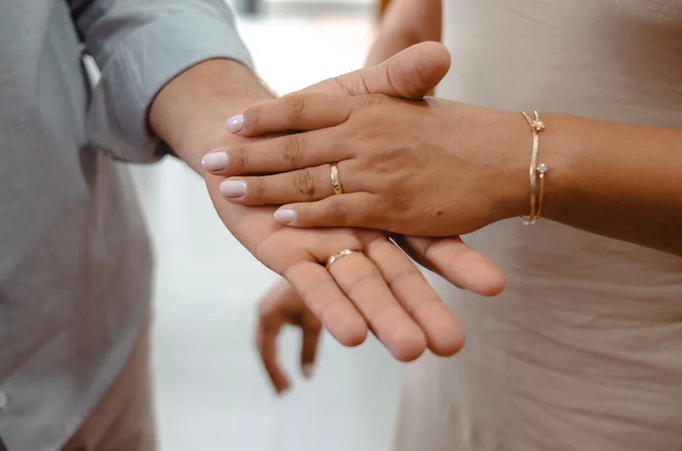 Two hands resting on each other, wedding rings on.