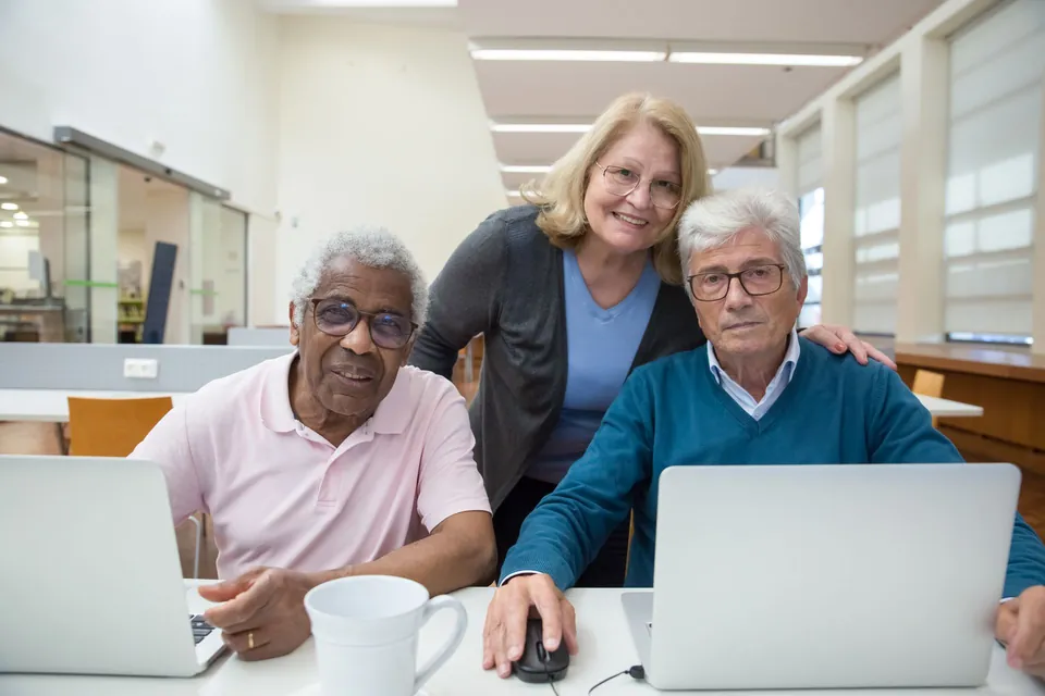 Trainer helping two participants at their laptops.
