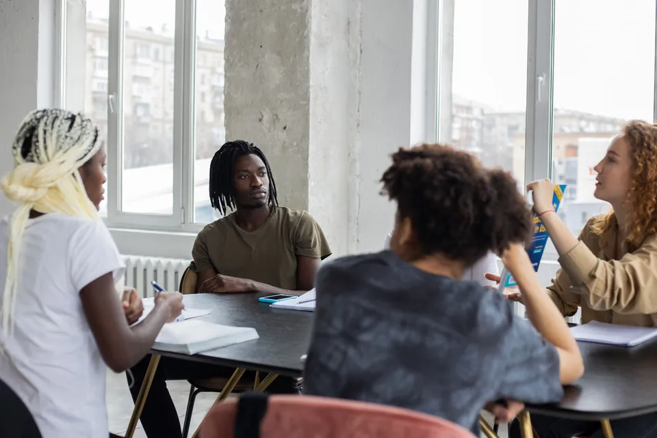 Group of students talking around a work table.