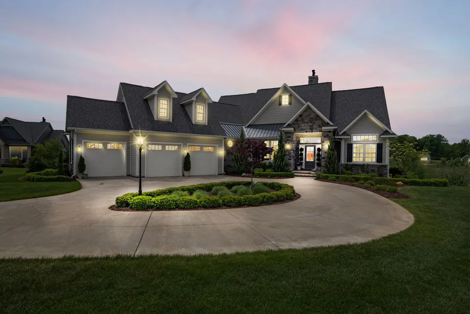 Detached house lit up at dusk, with a driveway and a lawn.