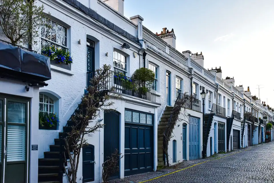 Cobbled lane lined with white townhouses with blue doors.