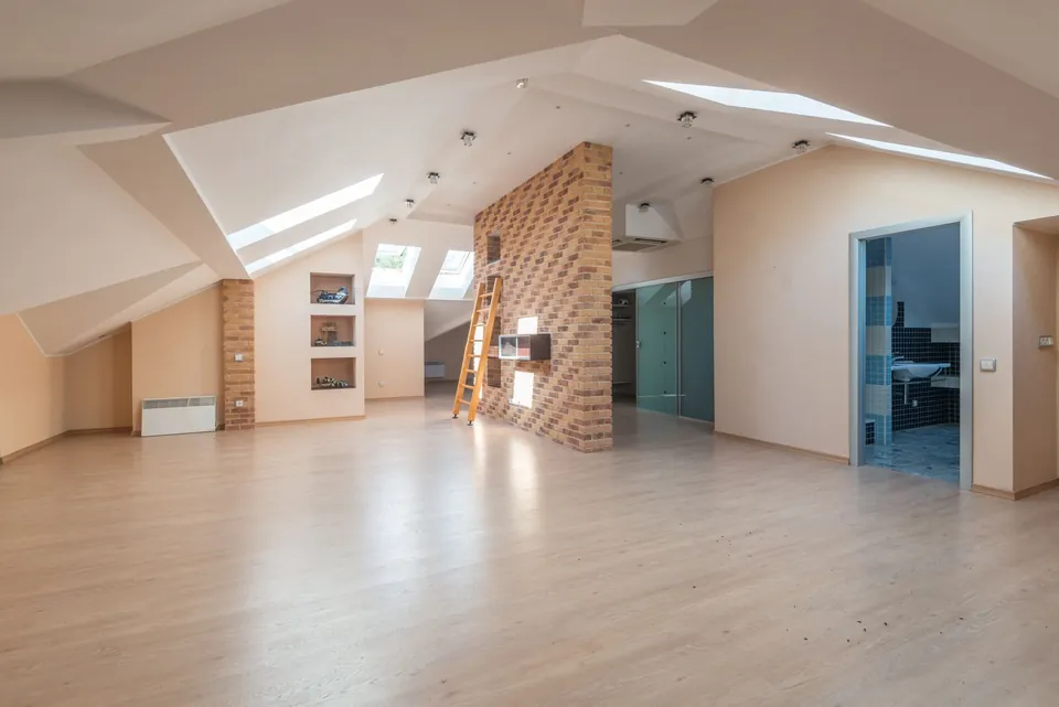 Large attic space with skylights and a brick wall.
