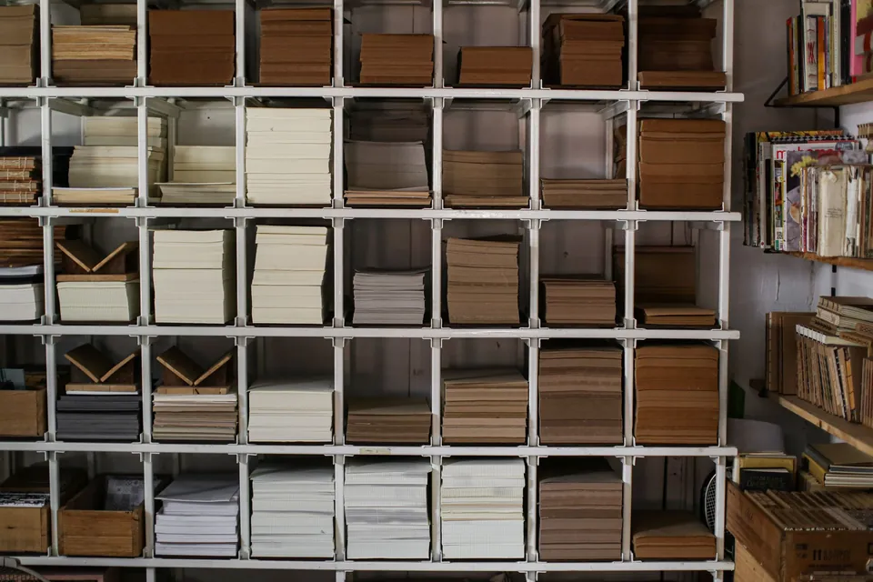 White shelving filled with stacks of cream and kraft paper.