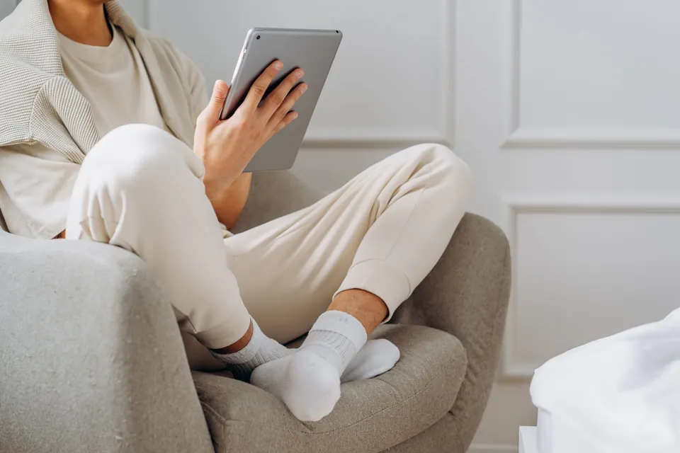 Person reading on a tablet, sitting in an armchair.