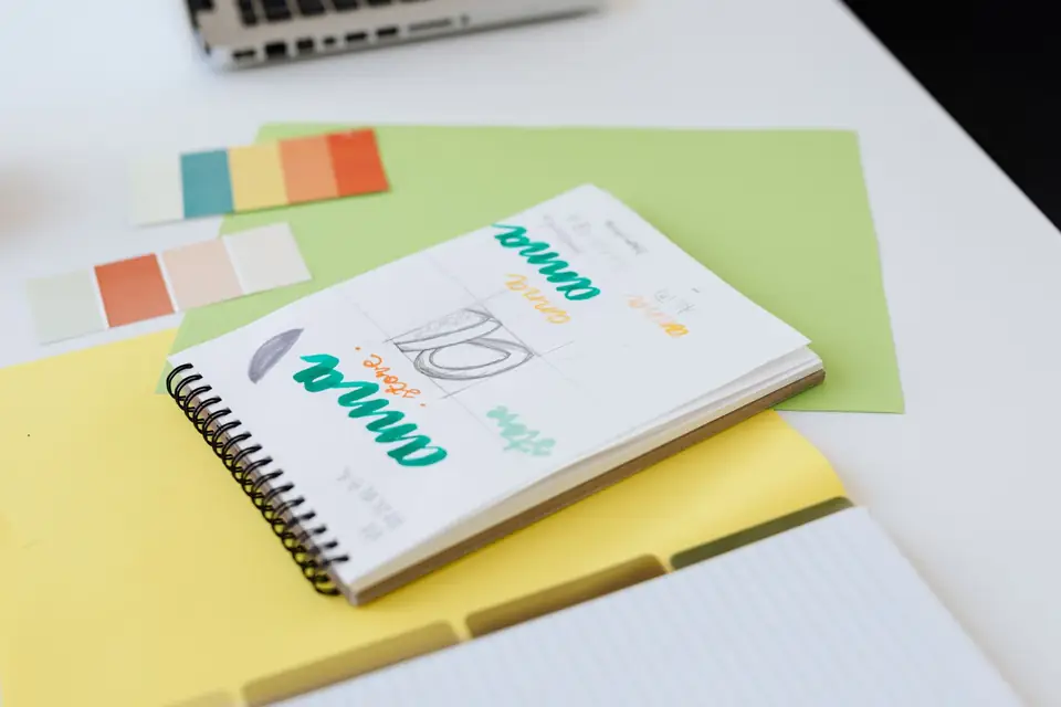 Logo sketchbook and colour swatches on a desk.