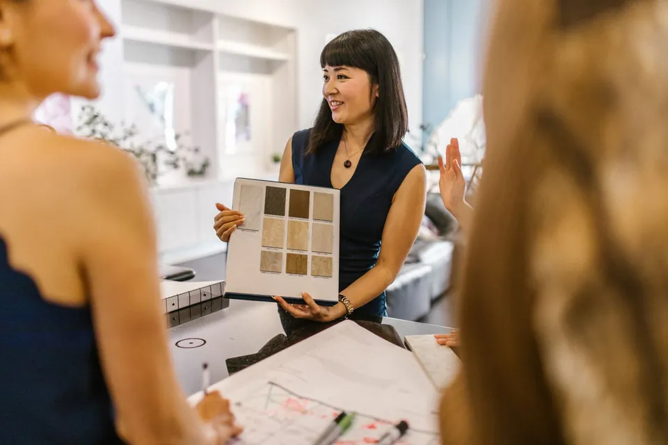 Designer presenting a colour and material board to two people.