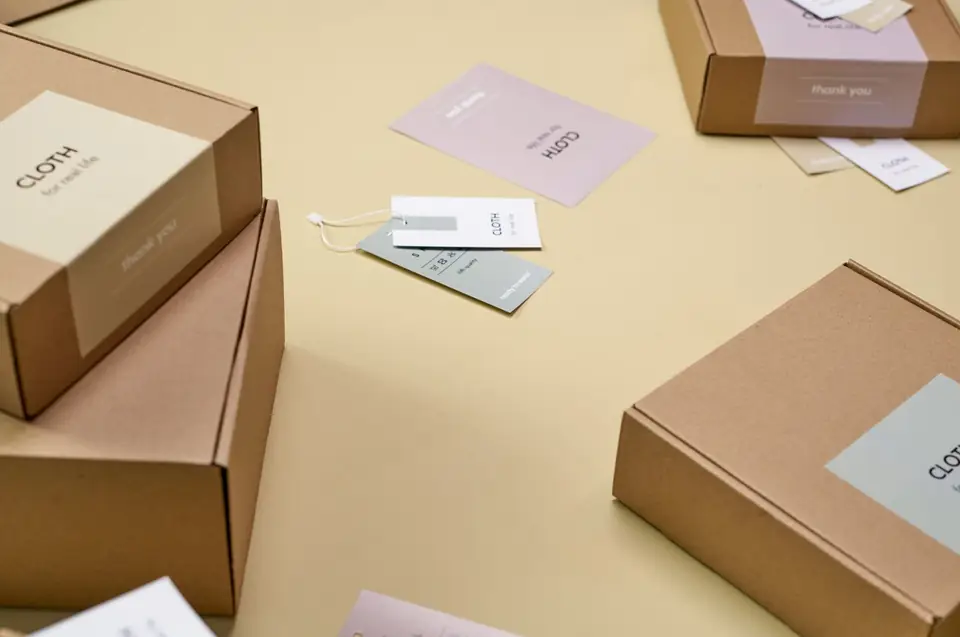 Labelled cardboard shipping boxes and brand cards on a yellow surface.