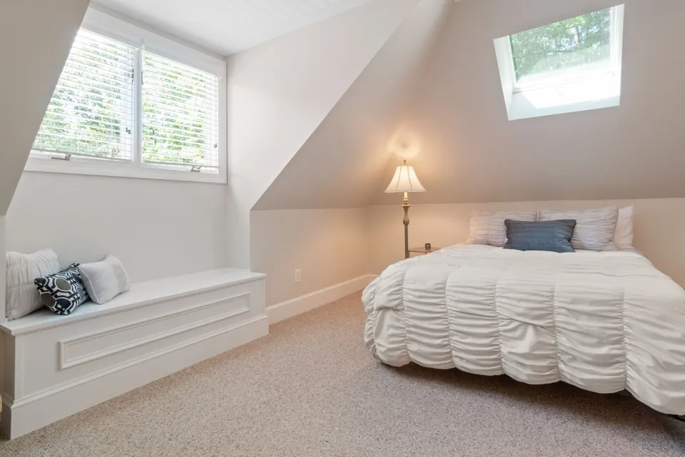 Bedroom fitted out in the attic, with a roof window and a window seat.
