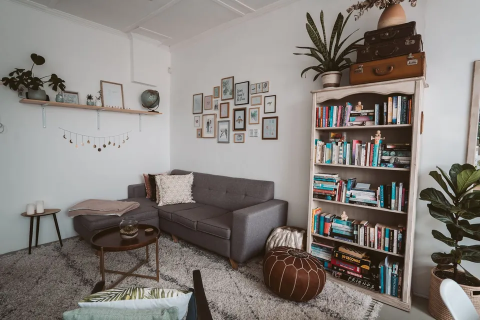 Cosy lounge with a grey sofa, a bookcase and plants.