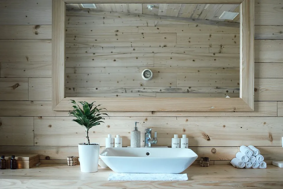 White basin, rolled towels and a plant on a wooden counter.