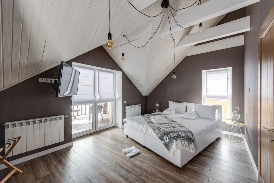 Attic bedroom with a white panelled ceiling, a double bed and a French window.