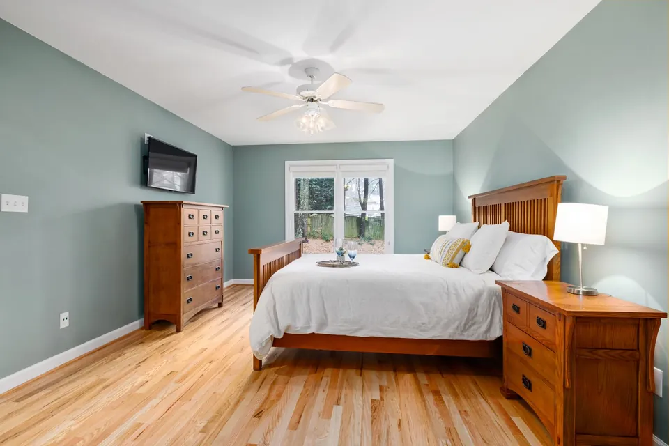 Bedroom with sage-green walls, a wooden bed and chests of drawers.