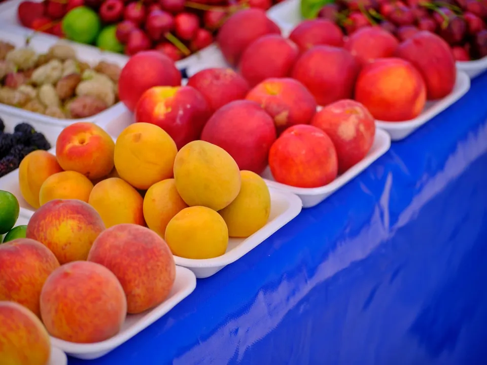 Peaches, apricots and nectarines in trays on a stall.