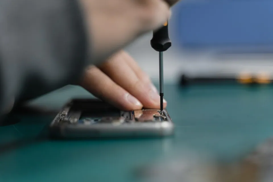 Technicien ouvrant un smartphone avec un outil de précision.