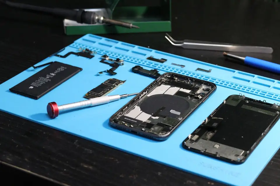 Opened smartphone and spare parts on a repair mat, tools alongside.