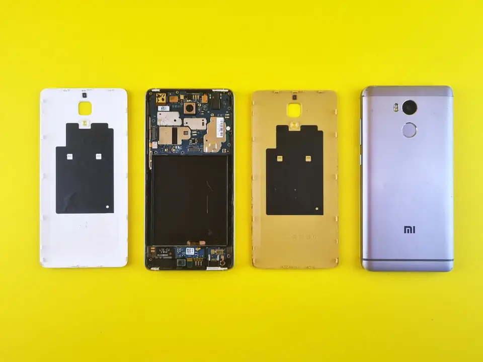 Disassembled smartphone: covers and motherboard lined up on a yellow background.