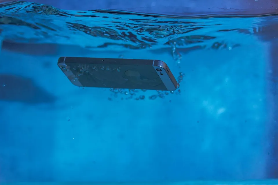 Smartphone sinking underwater, surrounded by bubbles.