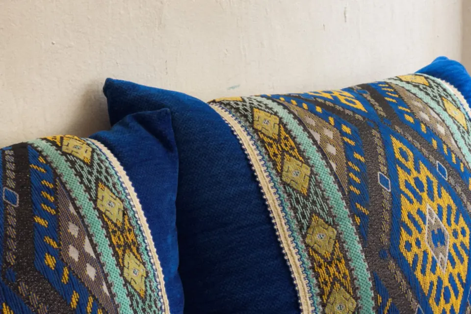 Close-up of embroidered cushions with blue and yellow patterns.