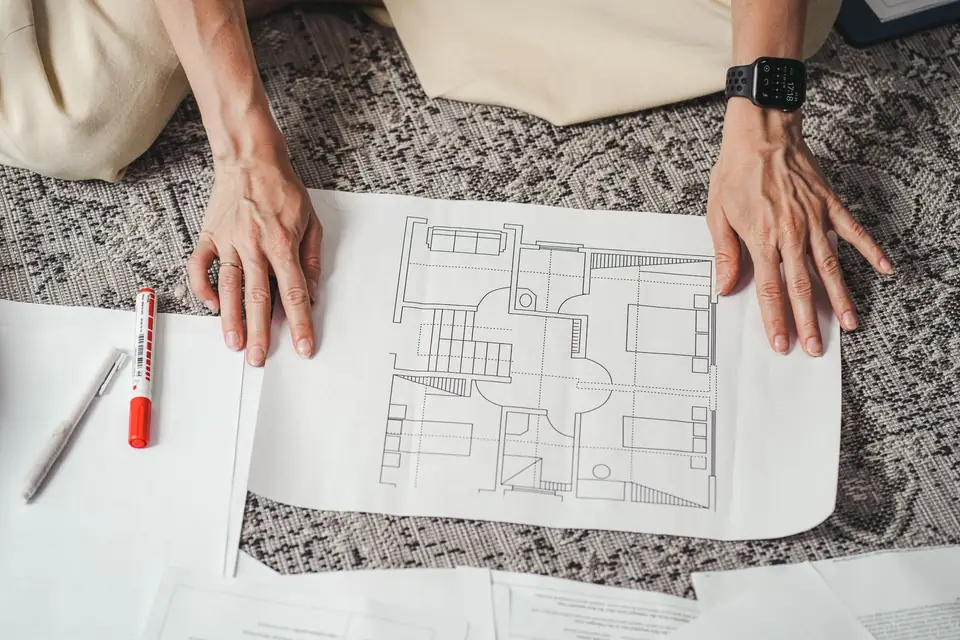 Hands resting on a printed house floor plan.