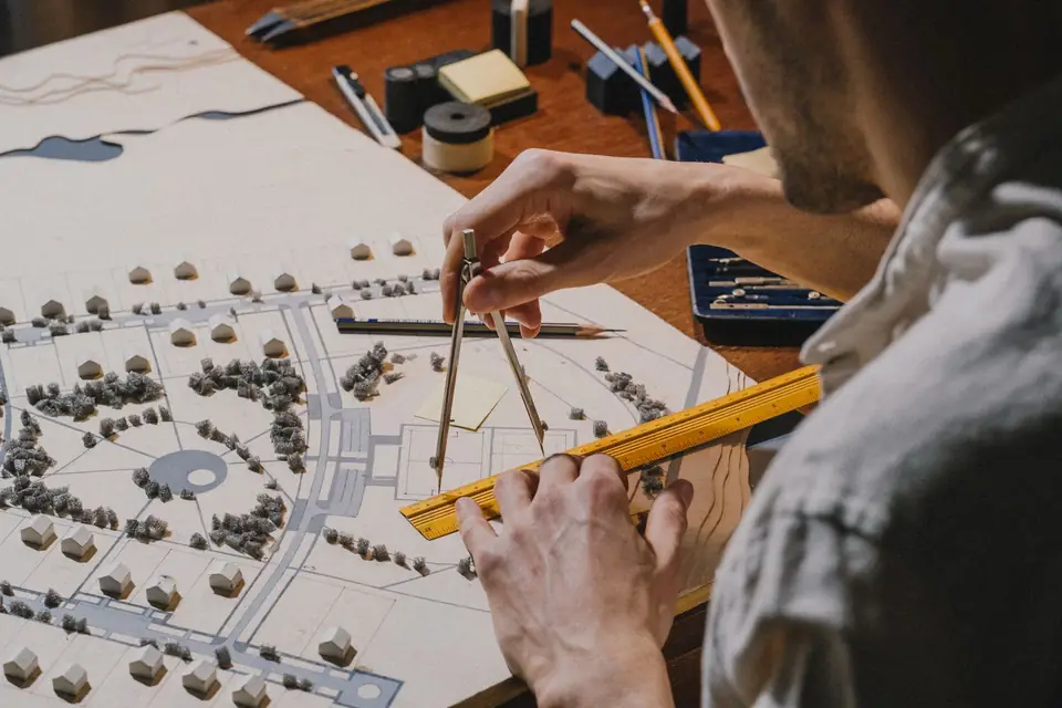 Architect working with a compass on an urban planning model.