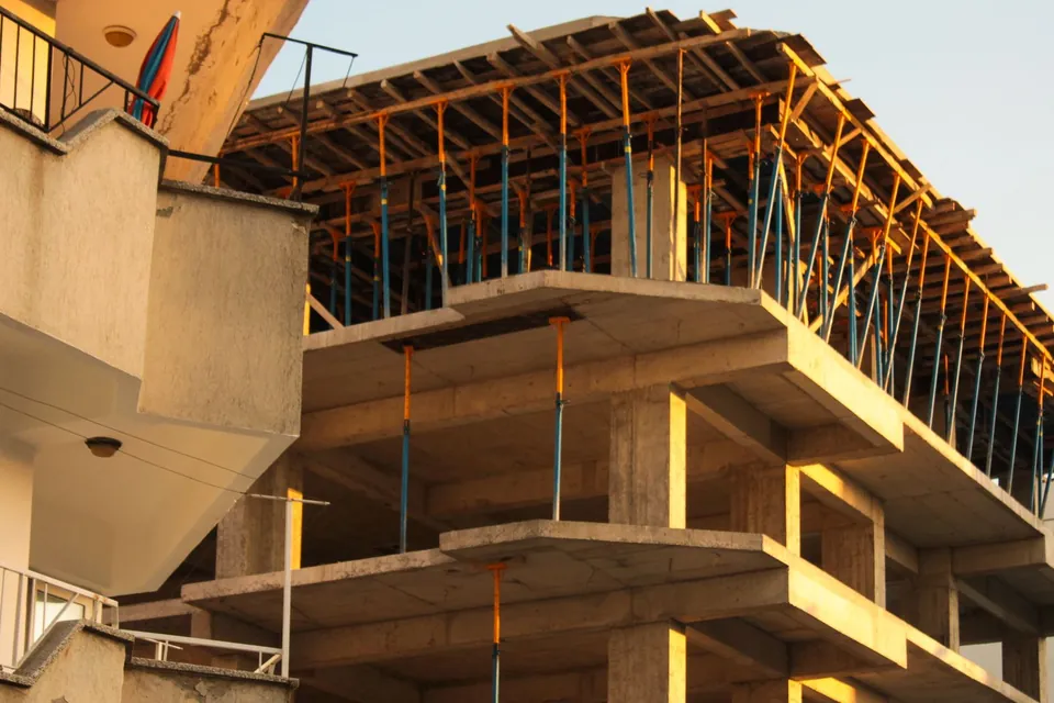 Concrete frame of a building under construction, formwork and props on the top floor.