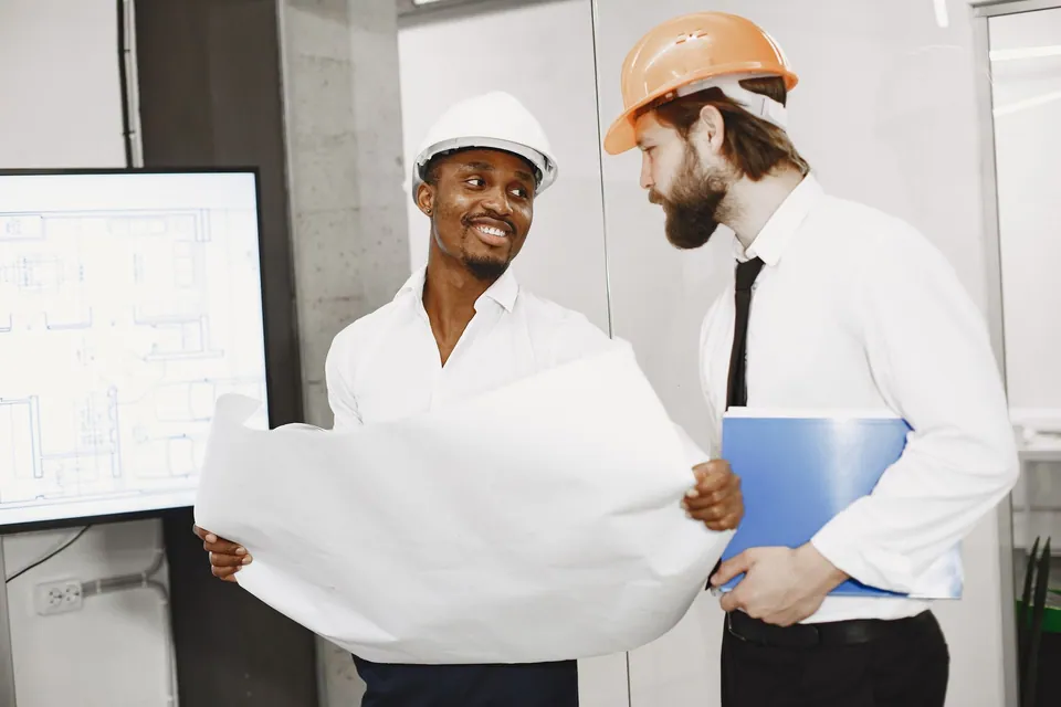 Professionnels de la construction comparant un plan sur chantier.