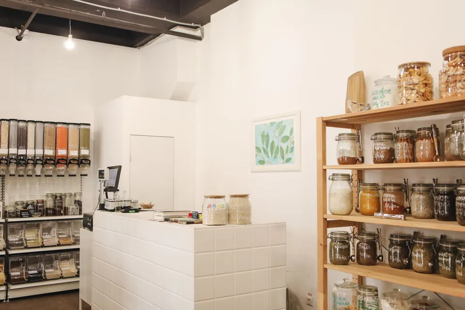 Small fitted-out shop: white counter, bulk dispensers and wooden shelves of jars.