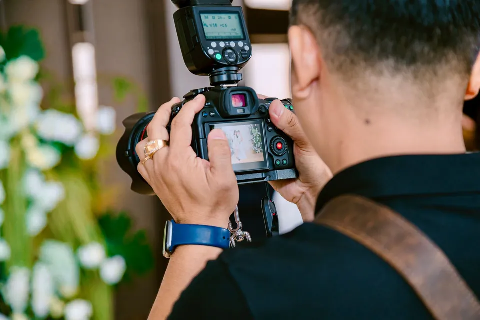 Wedding photographer checking a shot on the camera screen, seen from behind.