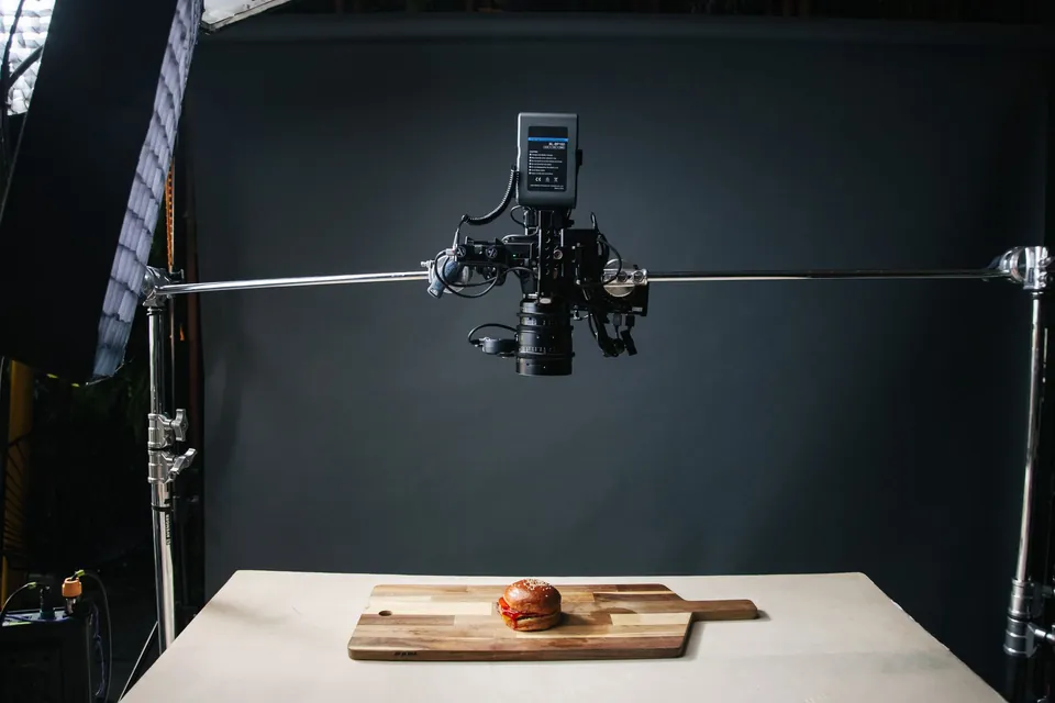 Food shoot set-up: camera on a boom arm above a burger on a board.