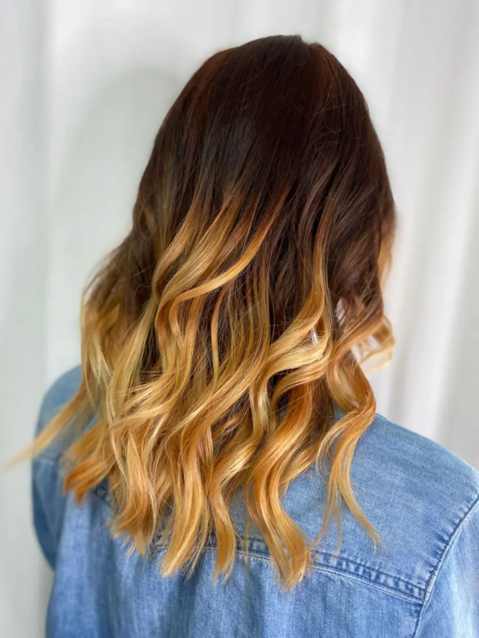 Long wavy brown hair with blonde ends, seen from behind.