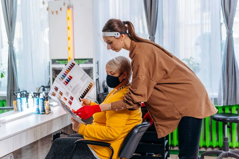 Stylist showing a hairstyle catalogue to a seated client.