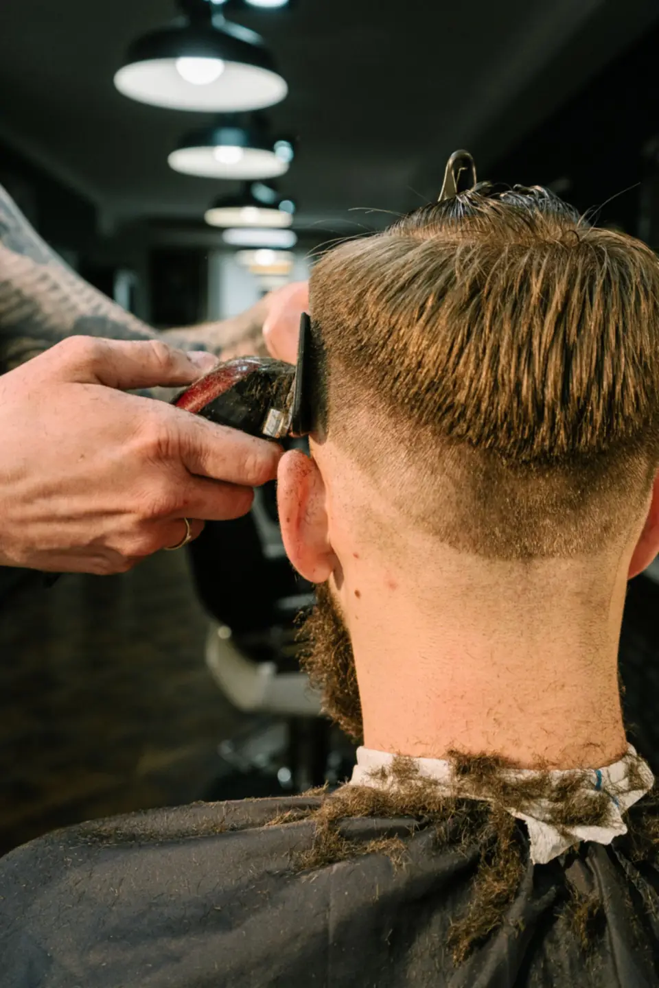 Barber clipping a client’s nape into a clean fade.