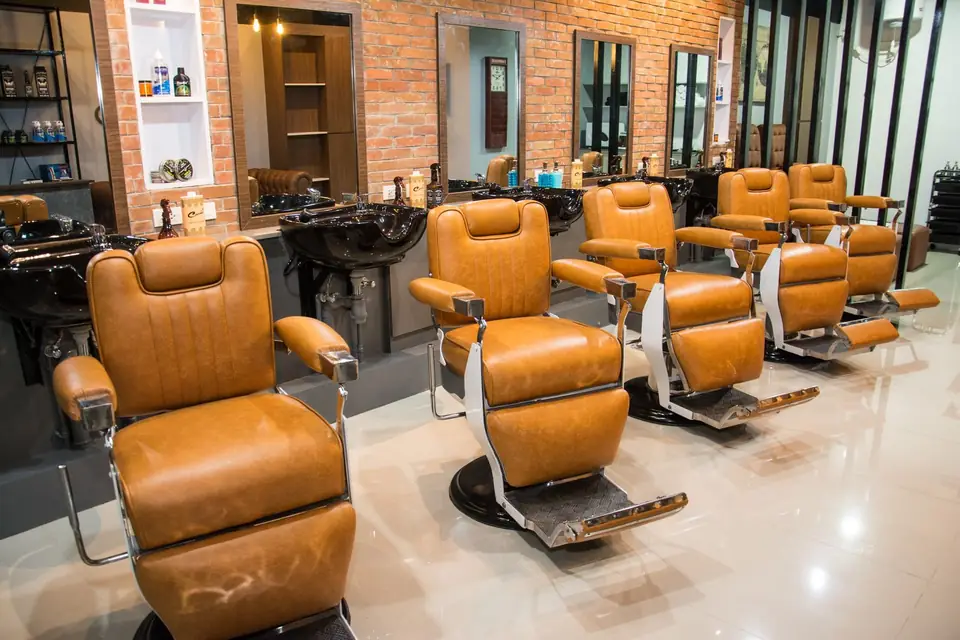 Row of tan leather styling chairs facing the mirrors.