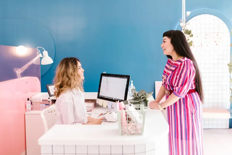 Client talking with the receptionist at a salon front desk.